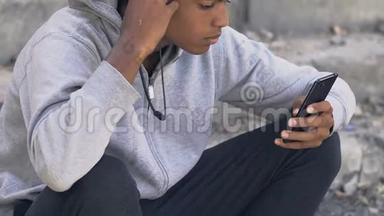 孤独沮丧的黑人青少年在耳机听智能手机音乐，抑郁